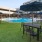 tables and chairs on lawn next to swimming pool